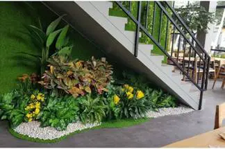 A garden with small shurbs placed below staircase