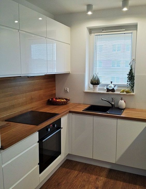 Kitchen designed in alternate pattern white base wooden countertop backsplash and white top storage