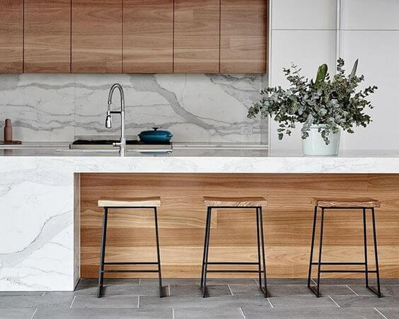 Natural Italian marble coutertop and wooden base with bar stools in island kitchen