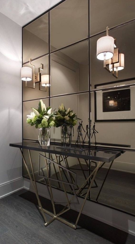 Mirror walls near entry with a small table and flower vase