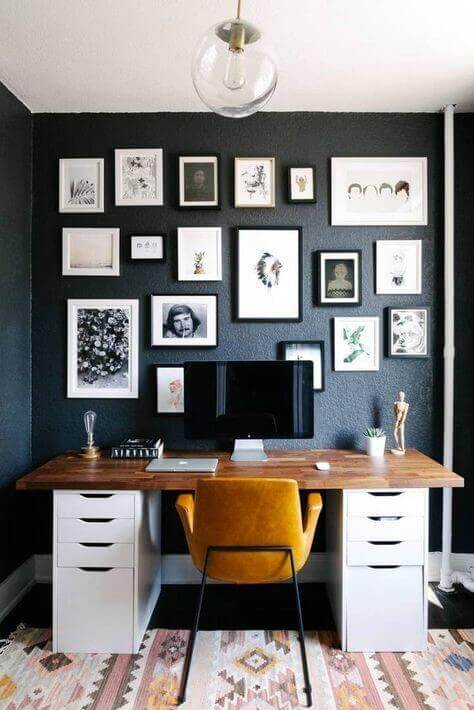 home office with dark colored wall and pictures on top