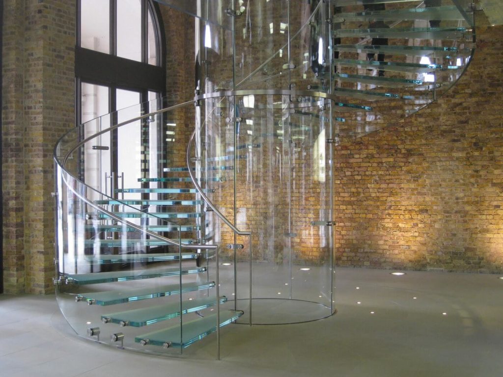 A glass staircase with glass steps, handrails and glass cylindrical structure in the middle