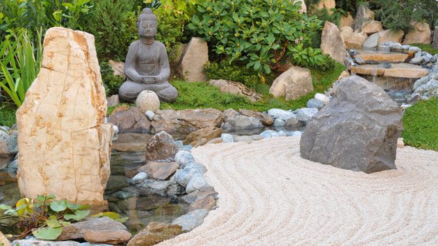 A zen garden decorated with stones, rocks and buddha statue