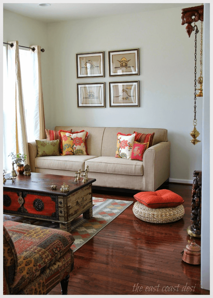 View of living room with off-white sofa and paintings with center table in the center