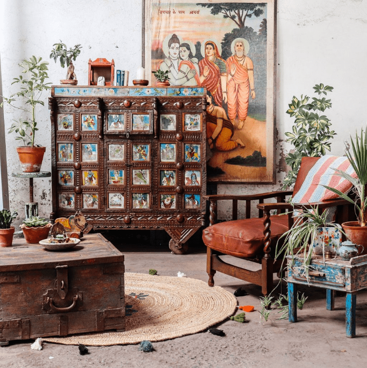 Beautiful view of an indian style home decoration with a wooden shelf with colourful designing and with a piece of art behind .